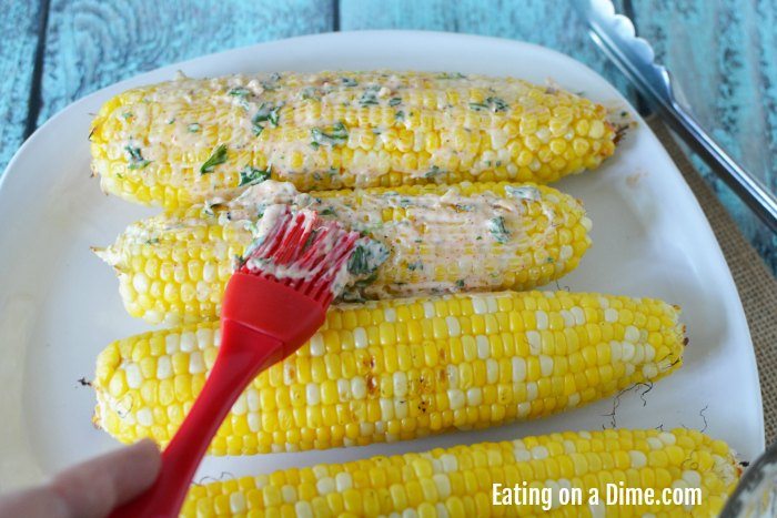 Close up image of Mexican Corn on the Cob with the seasoning being brushed on. 
