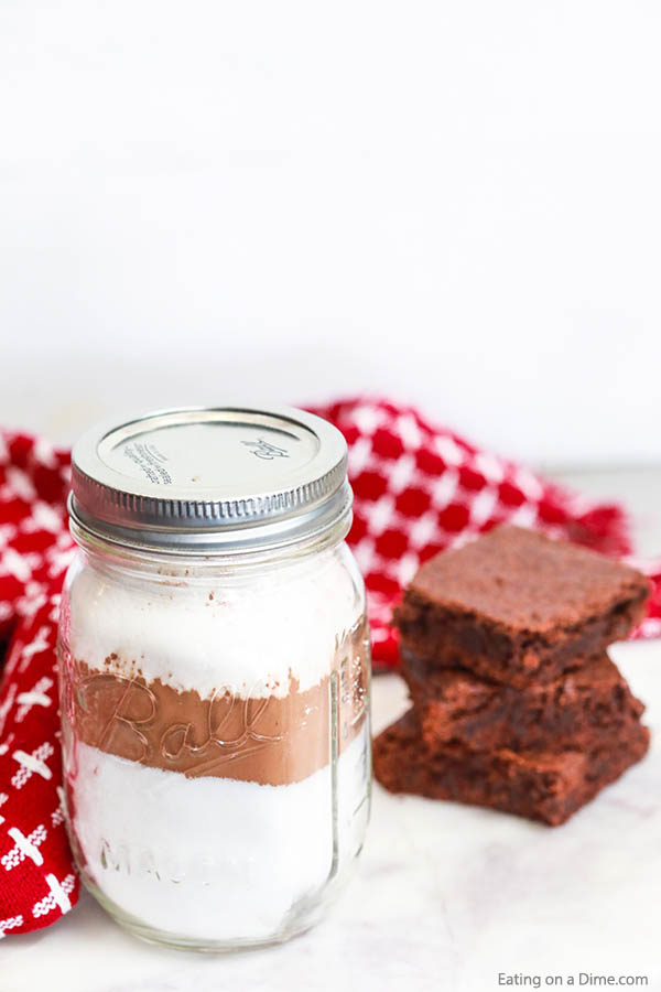 Close up image of brownie mix in a mason jar and brownies stacked. 
