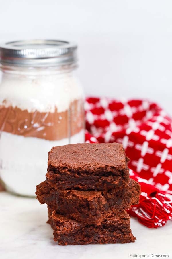Close up image of brownies stacked with a homemade brownie mix in a mason jar. 