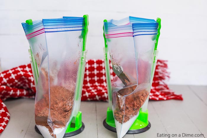 Close up image of ziplock baggies in freezer bag holders in process of putting the ingredients in the bag. 