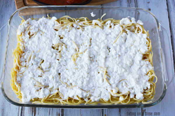 Baking dish with noodles and cheese mixture on top.