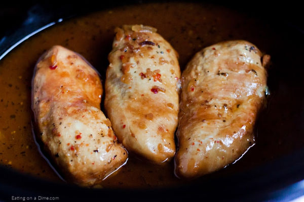 Close up image of 3 chicken breast in a crockpot cooked. 
