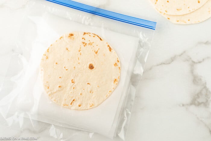 Tortillas with parchment paper in between them in a freezer bag. 
