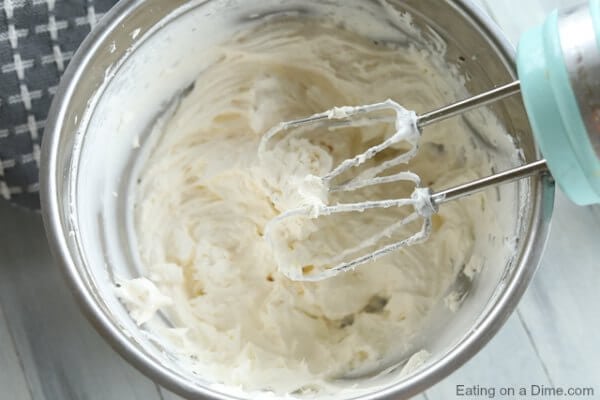 Close up image of cool whip and cream cheese being mixed together. 