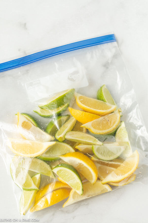 Learn how to freeze lemons and limes either whole or in slices. I love freezing citrus to save to use for juice, zest or for water. How to freeze lemons is easier than you think think! #eatingonadime #freezinglemons #freezingcitrus #freezertips 