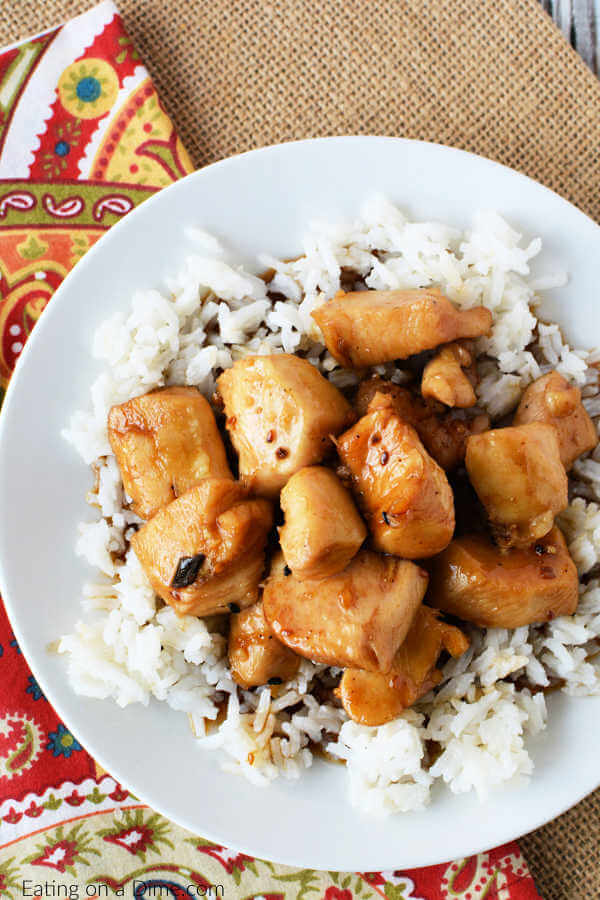 Close up image of a white plate of teriyaki chicken on a bed of rice. 