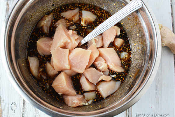 Close up image of chopped chicken being mixed with the teriyaki chicken with a spoon. 