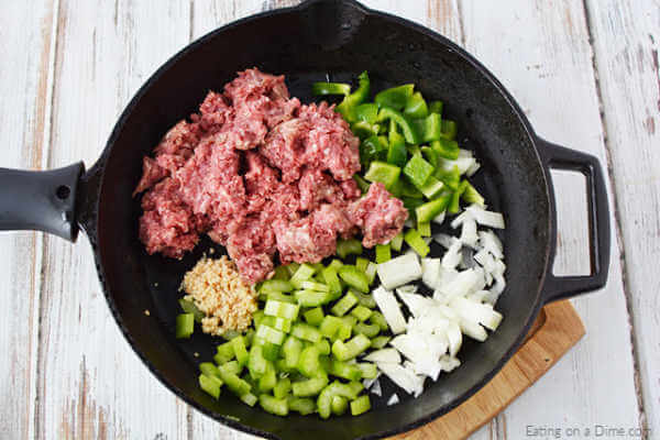 Close up image of uncooked beef and veggies in a skillet. 
