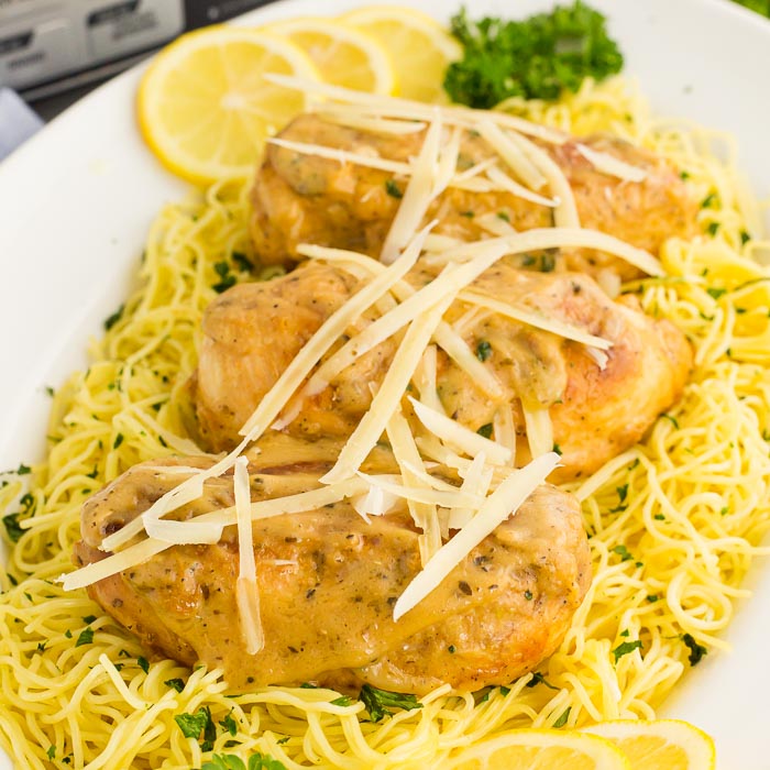 Lemon chicken on spaghetti noodles on a plate