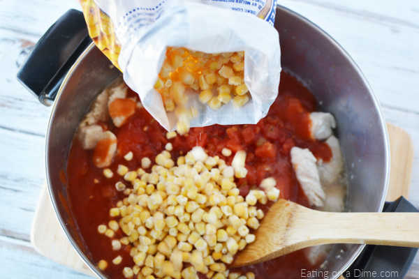 The tomato sauce and corn being added to the browned chicken in the stock pot. 