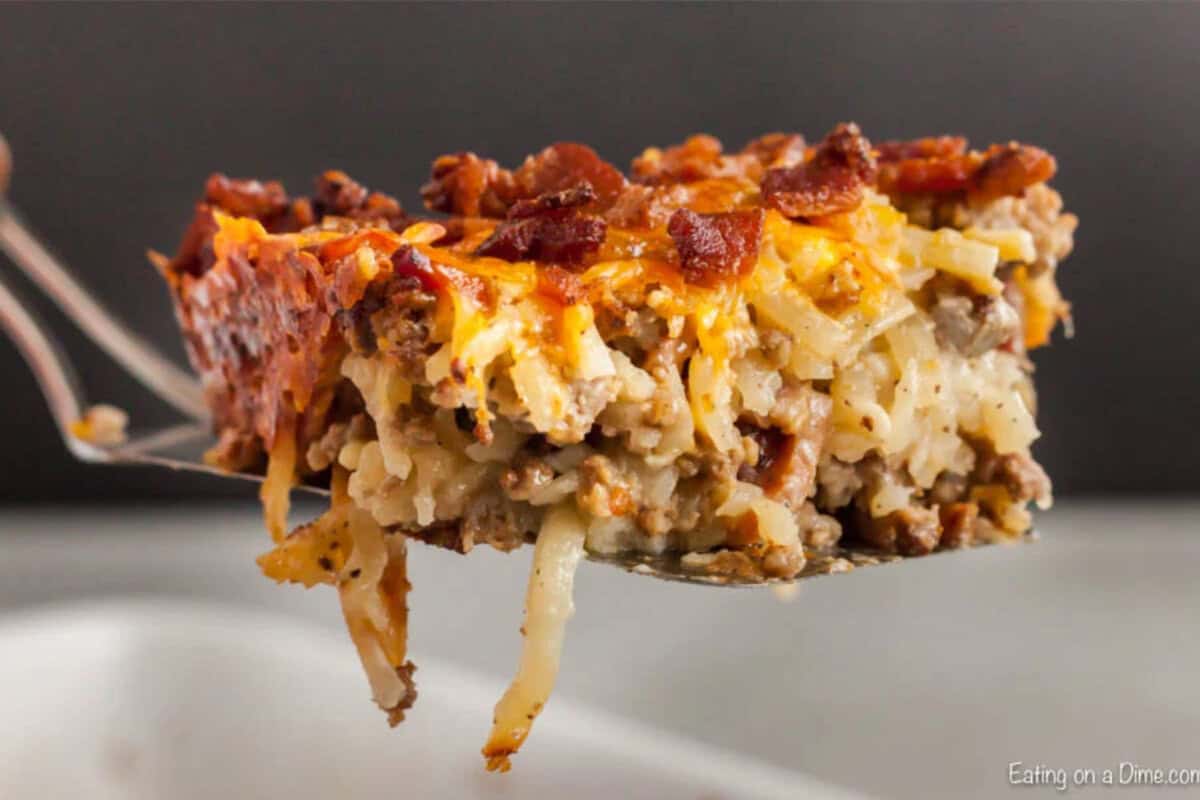 Bacon cheeseburger casserole recipe has everything you love about cheeseburgers in a tasty and easy casserole dish. This is a must try recipe! Spatula with bacon cheeseburger casserole serving on it.