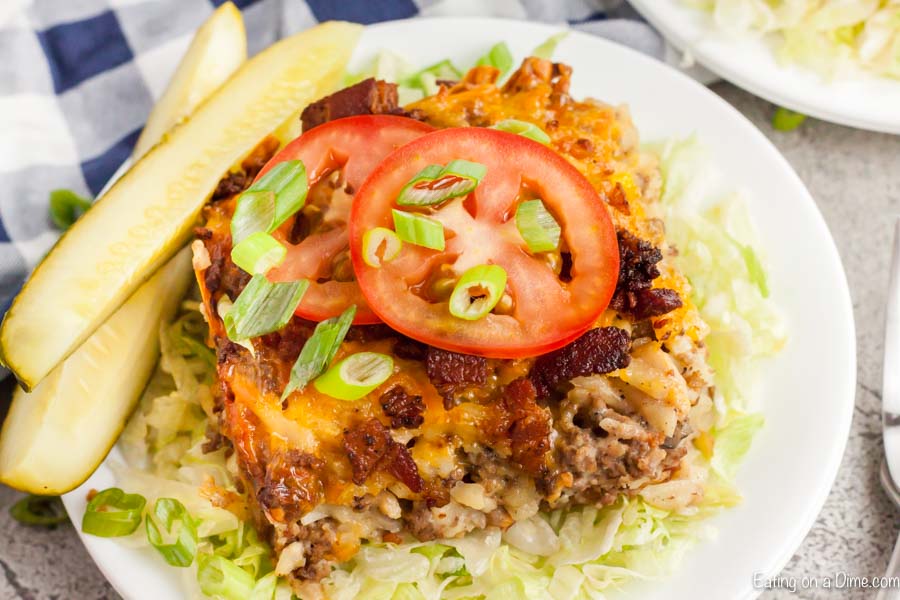 Serving of Cheeseburger casserole on a plate topped with tomatoes.