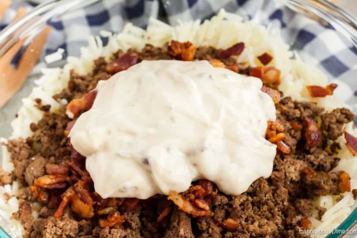 Bacon cheeseburger casserole recipe has everything you love about cheeseburgers in a tasty and easy casserole dish. This is a must try recipe! Hashbrowns, meat mixture and soup in a mixing bowl.