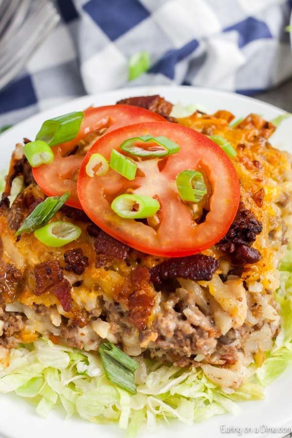 Serving of Cheeseburger casserole on a plate topped with tomatoes.