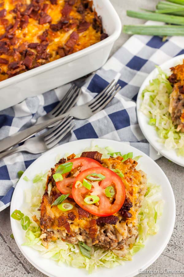Serving of Cheeseburger casserole on a plate topped with tomatoes.
