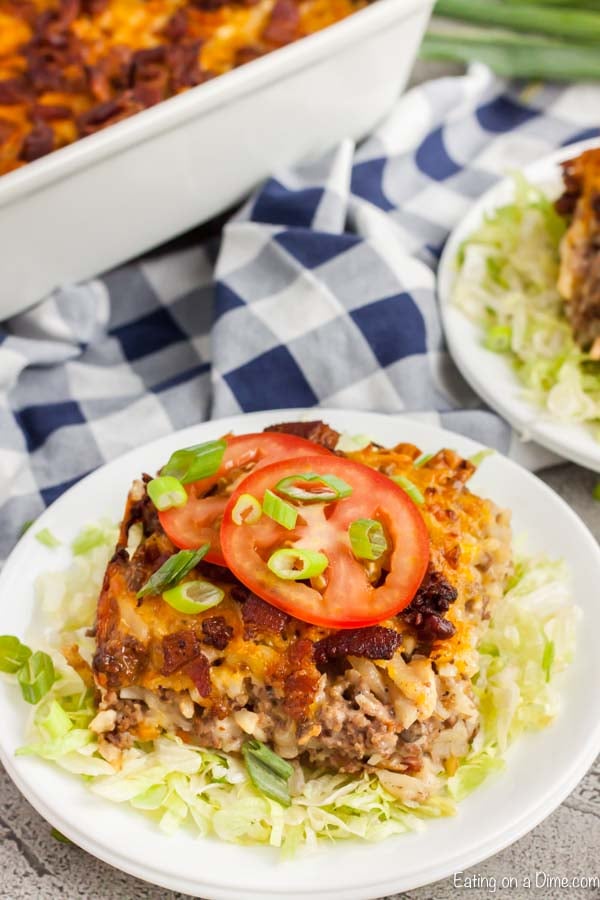 Serving of Cheeseburger casserole on a plate topped with tomatoes.