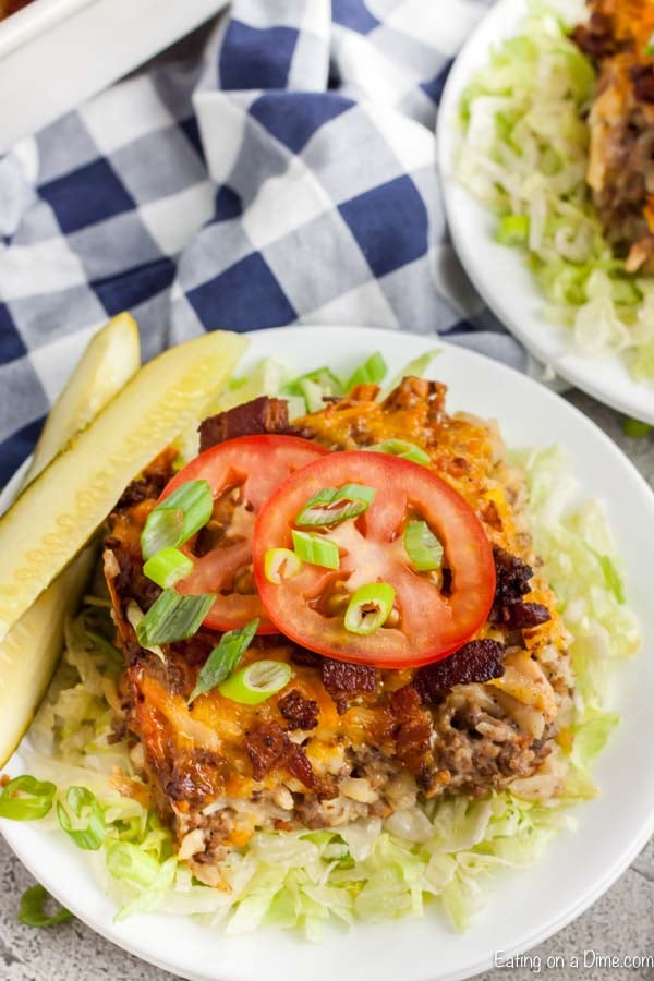 Serving of Cheeseburger casserole on a plate topped with tomatoes.