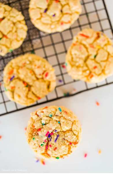 Photo of yellow cake mix cookies on wire rack with sprinkles.