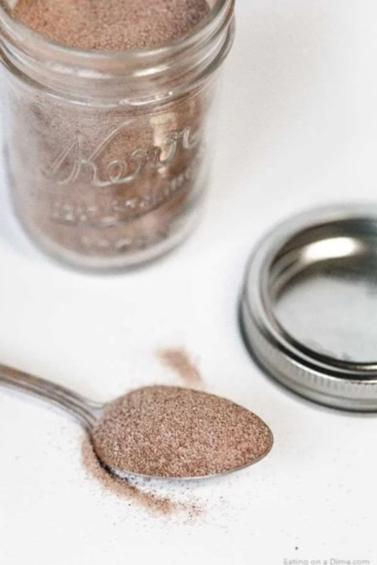 Learn how to make cinnamon sugar at home and save a ton of money. Skip the store bought mixture and make this in minutes. A jar of cinnamon sugar mixture with a spoon full of the mixture next to it.