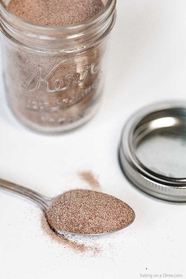 A jar of cinnamon sugar mixture with a spoon full of the mixture next to it. 