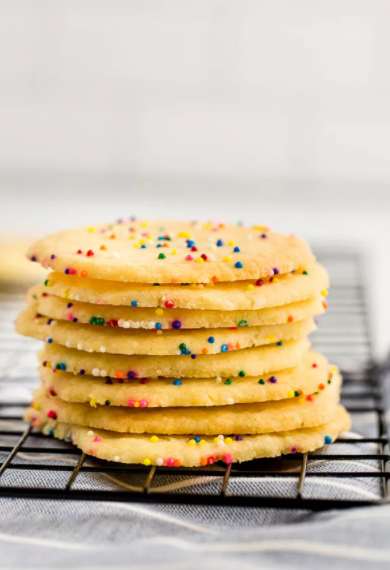 Photo of 3 ingredient sugar cookies stacked together on wire rack.