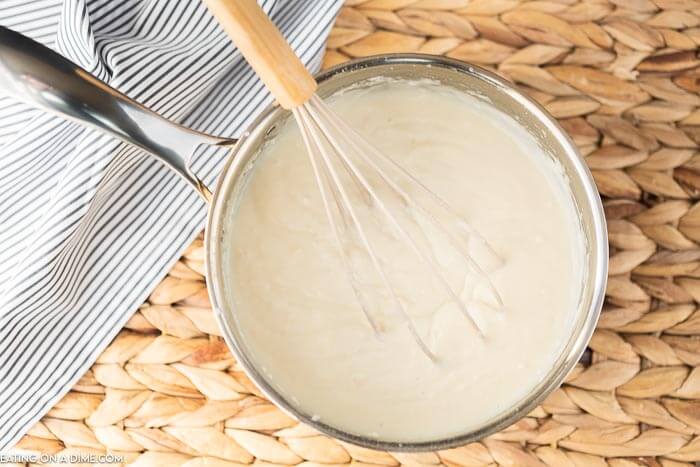 Close up image of gravy in a pan with a whisk.