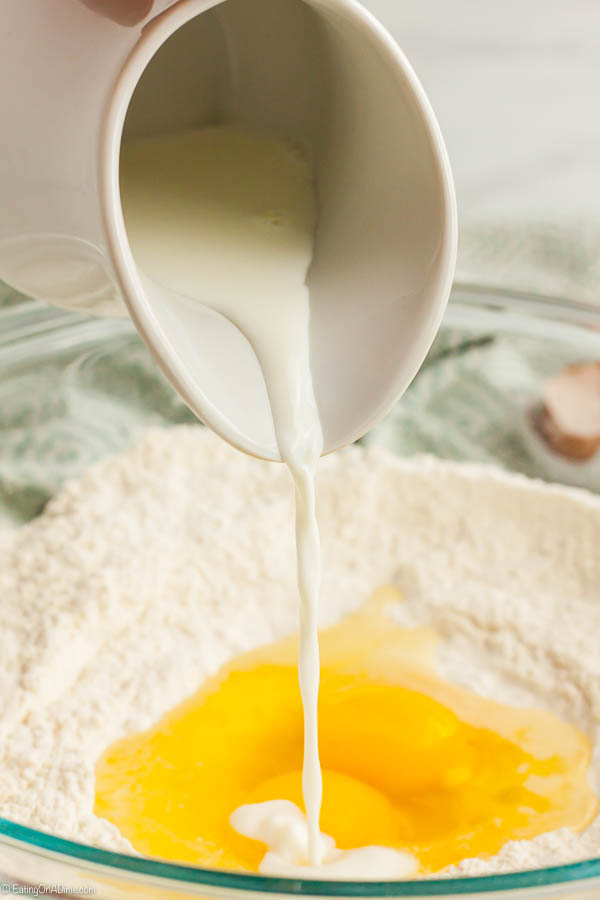 Pouring milk in a bowl with flour and egg