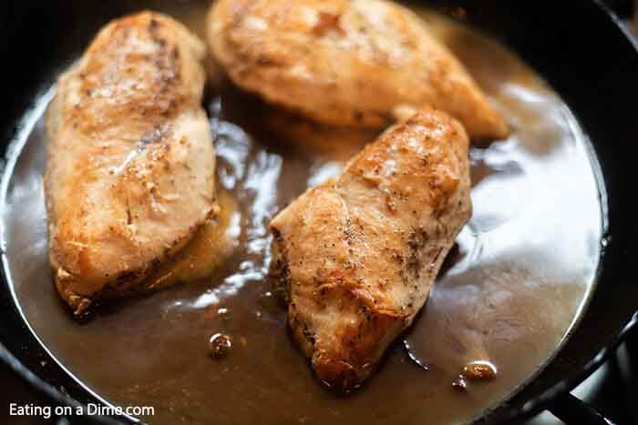 Golden brown chicken in a cast iron skillet in a brown sugar mixture