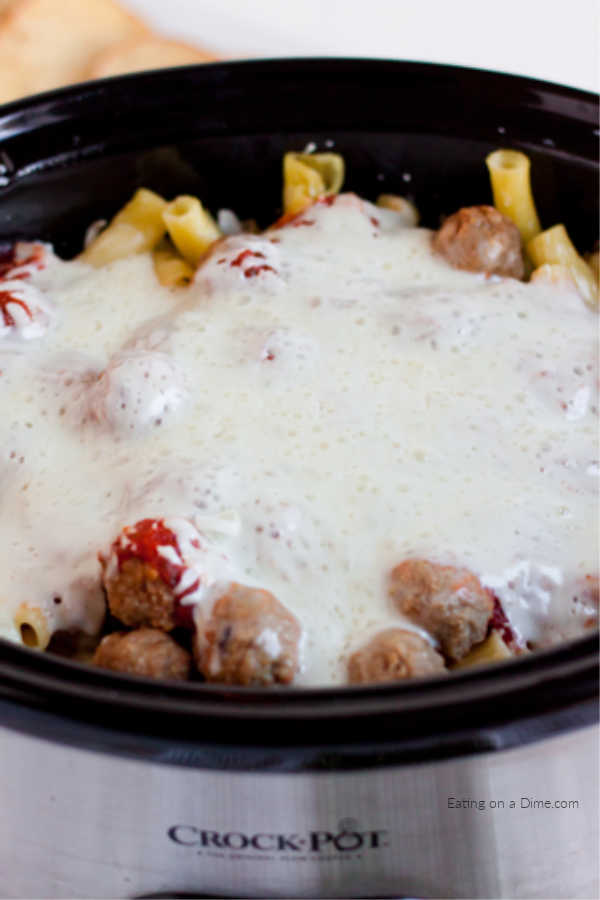 crockpot with pasta and meatballs topped with cheese