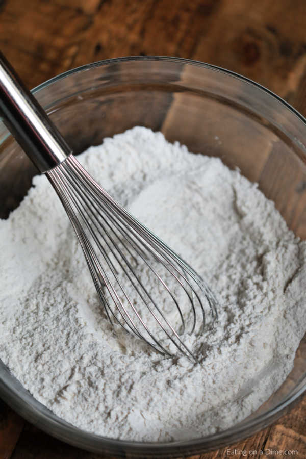 Powdered Pancake Mix in a clear bowl with a whisk. 