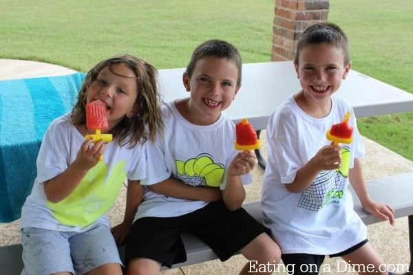 Cute kids enjoying popsicles on a picnic table outside