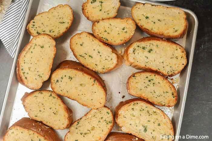 Learn how to make easy homemade cheesy garlic bread. This roasted homemade cheesy garlic bread recipe is the best DIY garlic bread. This home made french bread garlic bread recipe easy is better than Texas toast. Plus learn how to freeze garlic bread. You can make ahead and freeze this simple garlic loaf for later. Make and freezer for a quick and easy Side dish. Can you imagine having homemade garlic bread whenever you want? #eatingonadime #garlicbread #freezebread #freezerrecipes 