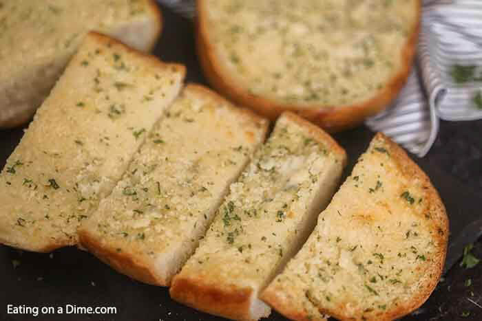 Learn how to make easy homemade cheesy garlic bread. This roasted homemade cheesy garlic bread recipe is the best DIY garlic bread. This home made french bread garlic bread recipe easy is better than Texas toast. Plus learn how to freeze garlic bread. You can make ahead and freeze this simple garlic loaf for later. Make and freezer for a quick and easy Side dish. Can you imagine having homemade garlic bread whenever you want? #eatingonadime #garlicbread #freezebread #freezerrecipes 