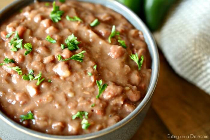 Learn how to make refried beans by cooking them in the crockpot! It is so easy to make Crock Pot refried beans and saves a ton of money. Bowl of refried beans.