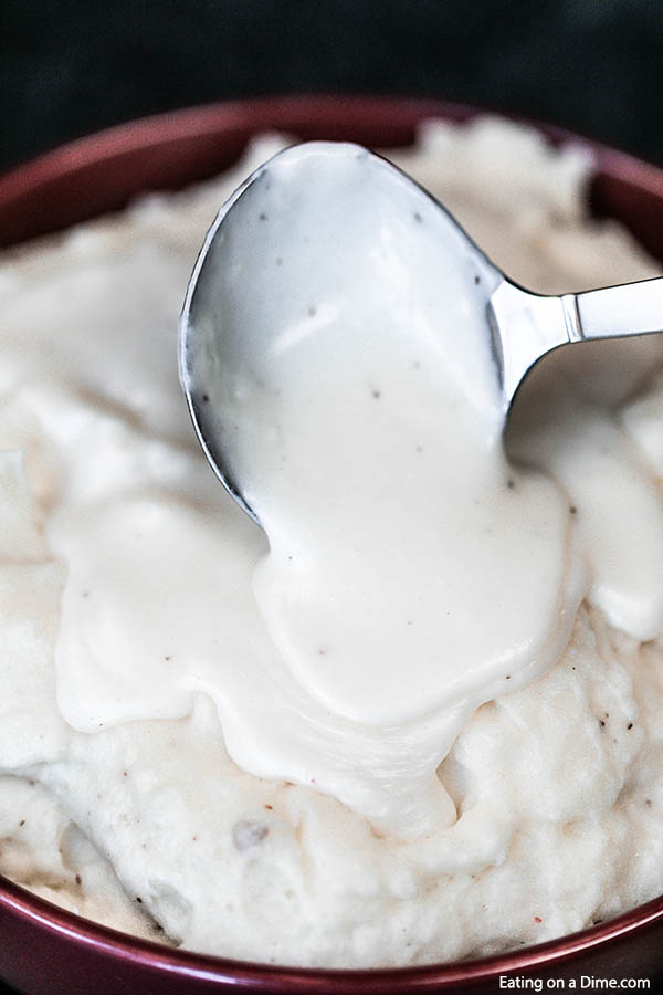 Pouring white gravy over mashed potatoes