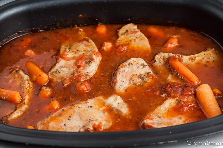 Cooking the pork chops and carrots in a tomato sauce in the slow cooker