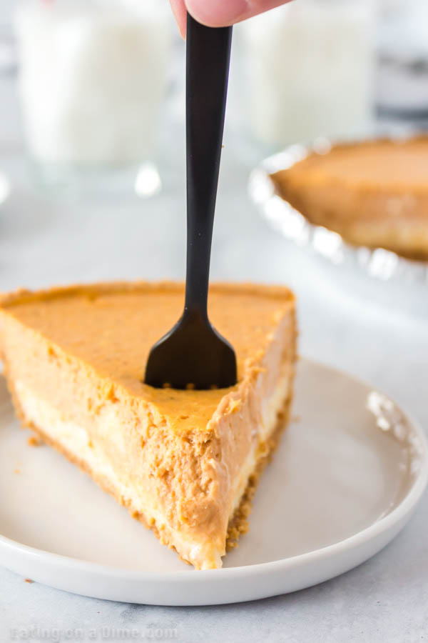 A fork taking a bite out of a slice of pumpkin cheesecake 