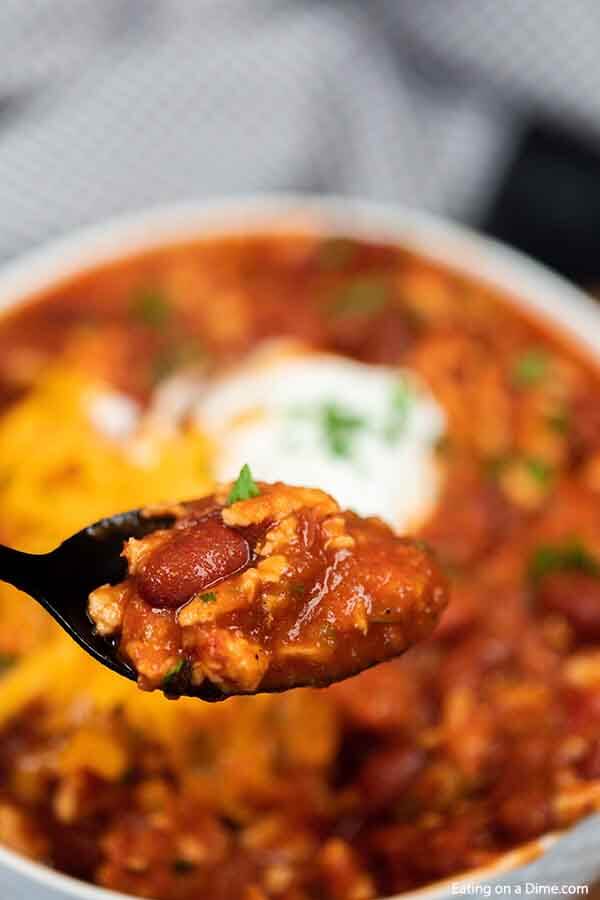 Close up image of ground turkey chili with a serving on a spoon. 