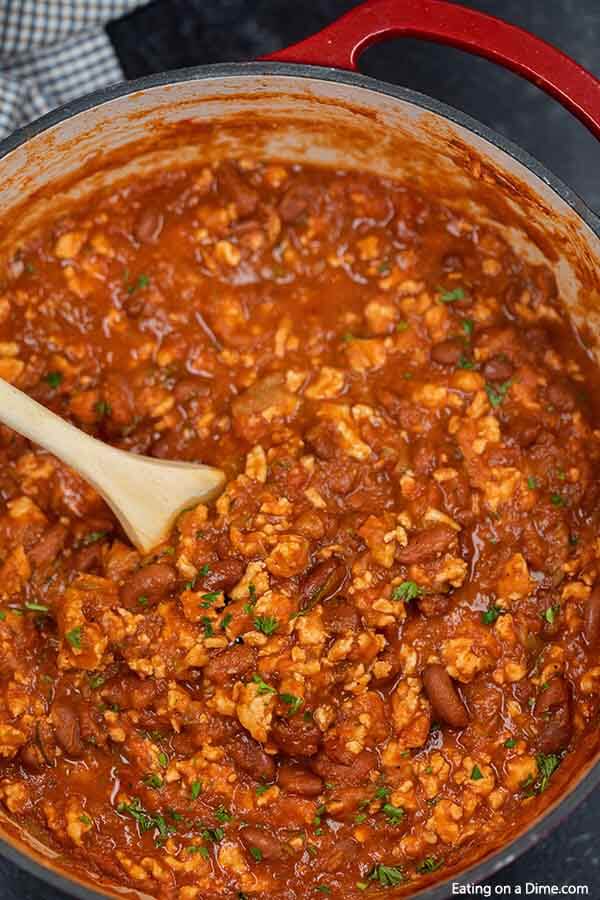 Close up image of a pot of turkey chili with a wooden spoon. 