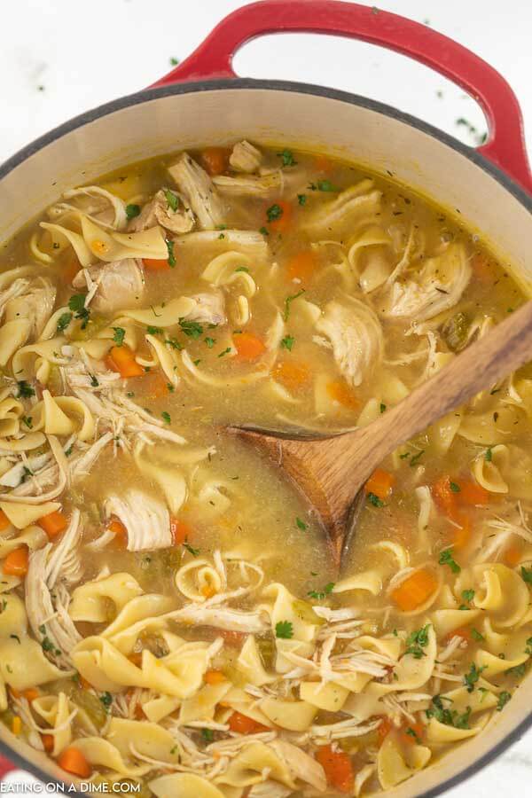 Dutch oven with chicken noodle soup with a wooden spoon