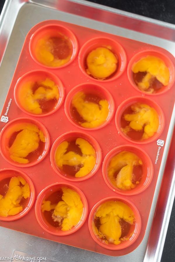 Egg yolk and egg white divided in a plastic muffin pan ready to freeze