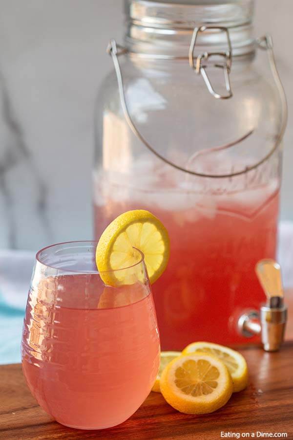Pink lemonade in a glass with a slice of lemons on the side