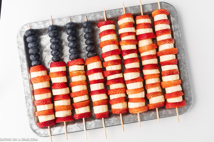 Photo of red, white and blue fruit layered on skewers to make a flag design. 
