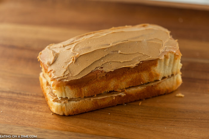 The other layer of pound cake has been placed on top of the bottom layer and peanut butter has been spread on the top of the cake.  