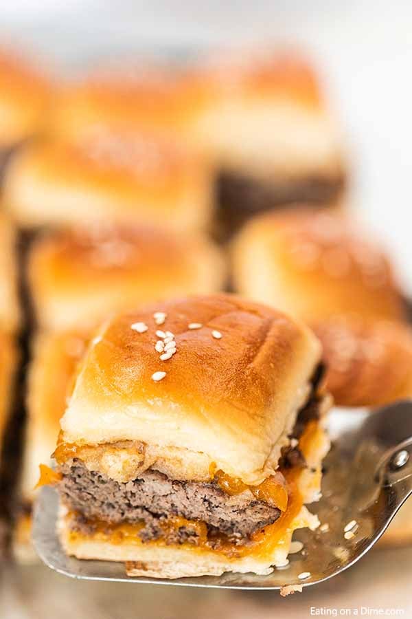 A cheeseburger slider being served on a spatula.  