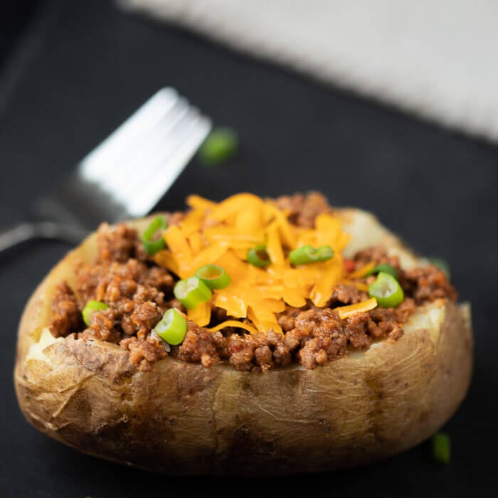 Meat topped onto a leftover baked potato topped with shredded cheese as well. 