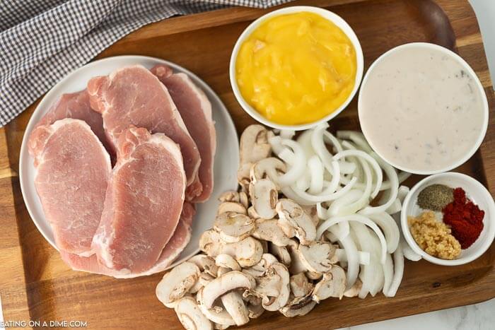 Ingredients needed for smothered pork chops - pork chops, sliced mushrooms, sliced onions, cream of mushroom soup, cream of chicken soup, beef broth, minced garlic, paprika pepper