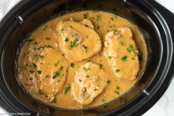 Close up image of smothered pork chops in a crock pot. 