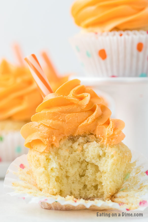 An orange soda cupcake with a bite take out of the middle of it 