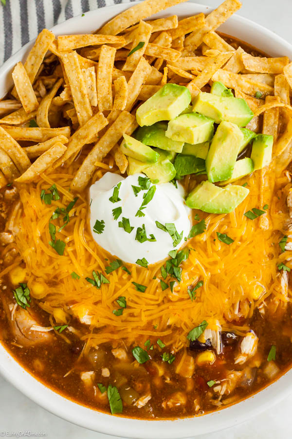 Bowl of Chicken Enchilada Soup topped with sour cream and tortilla strips. 